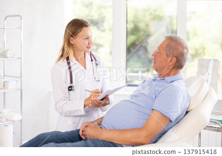 Female doctor with document folder talking to senior male patient Female doctor with document folder talking to senior male patient 137915418