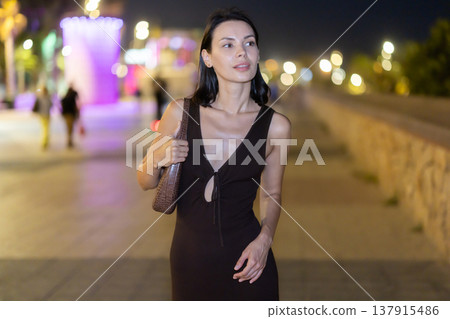 Woman walking along coastal promenade at night in Barcelona Woman walking along coastal promenade at night in Barcelona 137915486