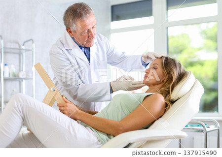 Elderly man doctor examining adult woman patient 137915490