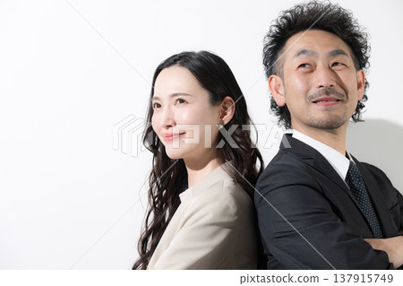 一男一女兩位商人背靠背站著，仰望著他們的目標和未來，背景是白色。 137915749