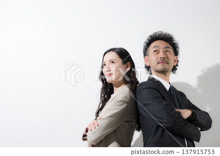 一男一女兩位商人背靠背站著，仰望著他們的目標和未來，背景是白色。 137915753