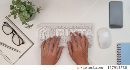 Typing on keyboard in organized workspace Typing on keyboard in organized workspace 137915786