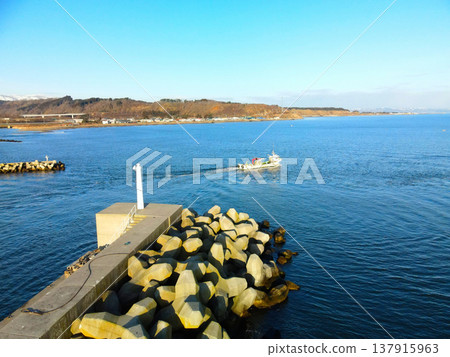 Aerial view of fishing boats entering and leaving Ochibe Fishing Port in Yakumo Town, Hokkaido, in early spring. Aerial view of fishing boats entering and leaving Ochibe Fishing Port in Yakumo Town, Hokkaido, in early spring. 137915963