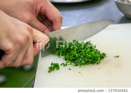 The chef's hands chopping parsley during cooking. 137916482