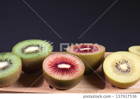 A platter of cross-sections of three different colored kiwifruits (on a black background) A platter of cross-sections of three different colored kiwifruits (on a black background) 137917536