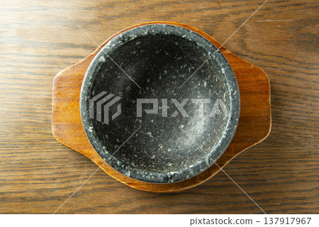 一個空的石鍋（石鍋）放在木托盤上，從上方拍攝。這是韓國料理、拌飯和嫩豆腐等傳統石製餐具。 137917967