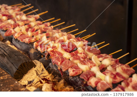 炭火上烤製的豬肉洋蔥串。商用烤架。逼真的場景，煙霧繚繞，火焰熊熊。想像酒吧或小吃攤的場景。 137917986