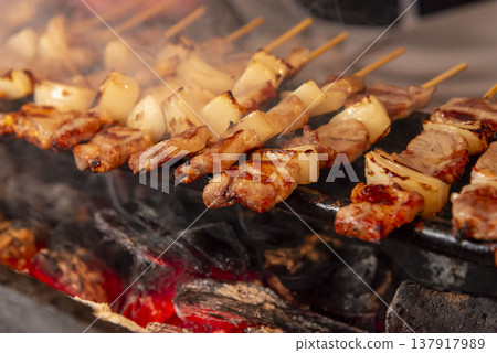 Grilled pork and onion skewers over charcoal. Commercial grill. Realistic scene with smoke and flames. Imagine a pub or food stall. 137917989