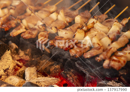 炭火上烤製的豬肉洋蔥串。商用烤架。逼真的場景，煙霧繚繞，火焰熊熊。想像酒吧或小吃攤的場景。 137917990