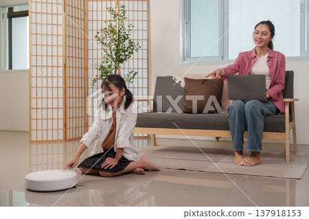 Mother and daughter interacting with a robotic vacuum cleaner Mother and daughter interacting with a robotic vacuum cleaner 137918153