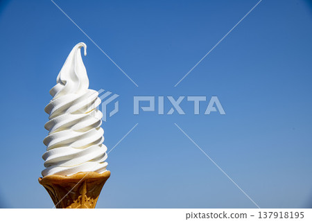 Soft serve ice cream against a blue sky: Hokkaido milk soft serve. Summer blue sky and ice cream. Tourist sweets. Soft serve ice cream against a blue sky: Hokkaido milk soft serve. Summer blue sky and ice cream. Tourist sweets. 137918195