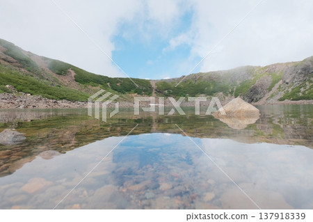 天空倒映在寧靜的山間池塘中。 137918339