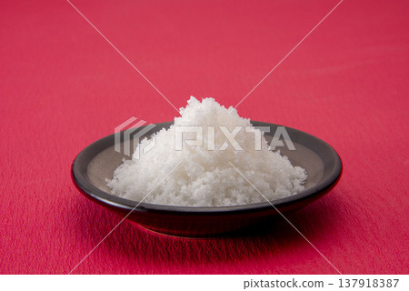 A small plate piled high with white salt; symbolizing purification, good fortune, and feng shui; a traditional Japanese custom. A small plate piled high with white salt; symbolizing purification, good fortune, and feng shui; a traditional Japanese custom. 137918387