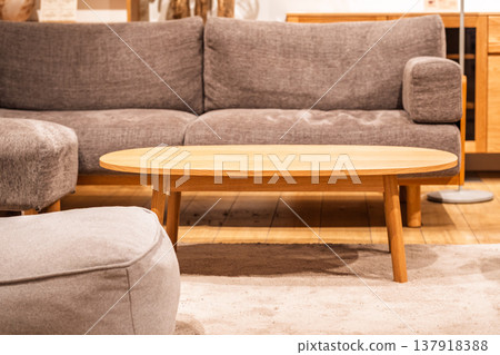 Scandinavian-style living room furniture: oval oak coffee table and gray sofa. Scandinavian-style living room furniture: oval oak coffee table and gray sofa. 137918388
