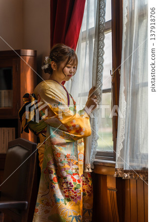 一位身穿振袖和服的 20 歲女子凝視著一棟復古的西式古董豪宅/工作室的窗外。 一位身穿振袖和服的 20 歲女子凝視著一棟復古的西式古董豪宅/工作室的窗外。 137918706