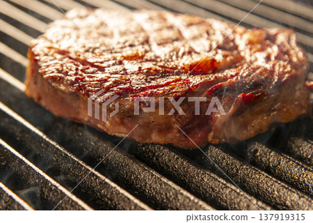 烤製前的生牛排；炙熱的烤架上冒出縷縷青煙；鐵板燒烹飪的真實場景。 137919315