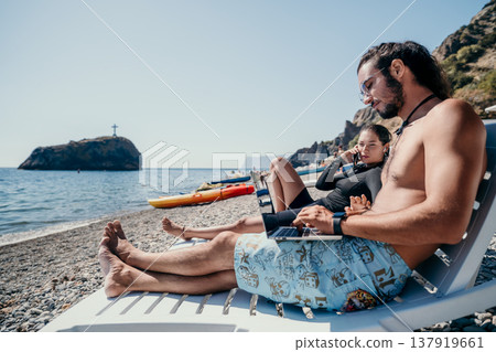 Couple Beach Relaxation - Man and woman relaxing on beach chairs near ocean with a lighthouse in the background. Couple Beach Relaxation - Man and woman relaxing on beach chairs near ocean with a lighthouse in the background. 137919661
