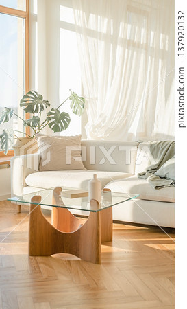 A bright, natural living room with a white sofa, monstera plant, glass table, and stylish Scandinavian-style interior. A bright, natural living room with a white sofa, monstera plant, glass table, and stylish Scandinavian-style interior. 137920132