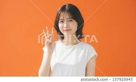 一張日本女性的自然肖像，她神態樂觀，背景是橘色。 137920945