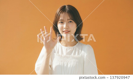 一張日本女性的自然肖像，她神態樂觀，背景是橘色。 137920947