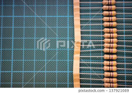 Row of resistors on carrier tape with copy space on cutting mat, electronic components background 137921089