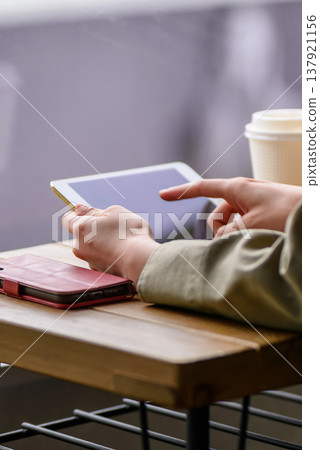 A woman who manipulates a tablet at a cafe A woman who manipulates a tablet at a cafe 137921156