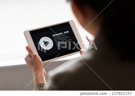 A woman watching a video on a tablet. 137921157