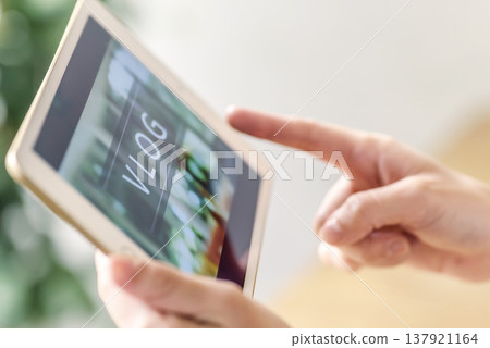一位女士正在用平板電腦觀看影片部落格。 一位女士正在用平板電腦觀看影片部落格。 137921164