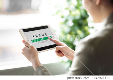 A woman checking trend information on her tablet. A woman checking trend information on her tablet. 137921180