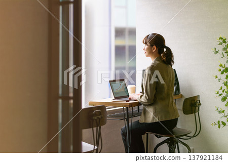 A woman working on a PC by the window 137921184