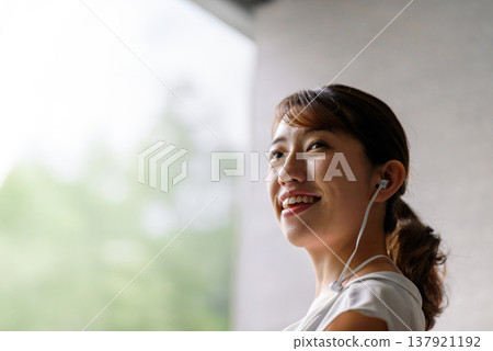 A woman smiling while listening to music with earphones. 137921192