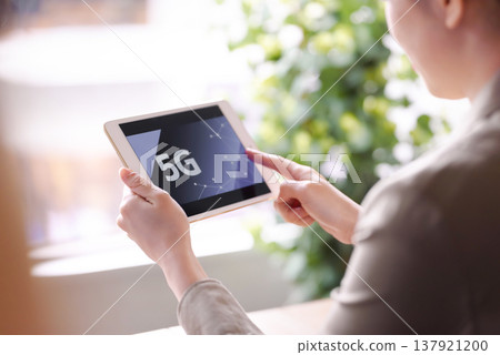 A woman checks 5G connectivity on her tablet. A woman checks 5G connectivity on her tablet. 137921200