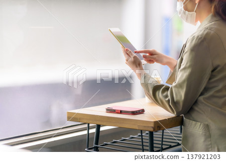 一位女士在咖啡館使用平板電腦和智慧型手機。 137921203