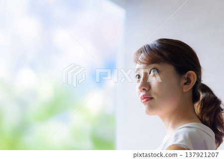 A woman gazing into the future from a window. 137921207