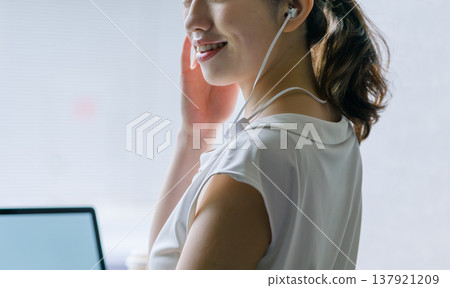 A smiling woman listening to music with earphones. 137921209