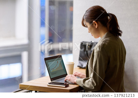 A woman is working on her PC by the window. A woman is working on her PC by the window. 137921213