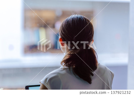 一名女子背對著鏡頭，盯著螢幕。 137921232