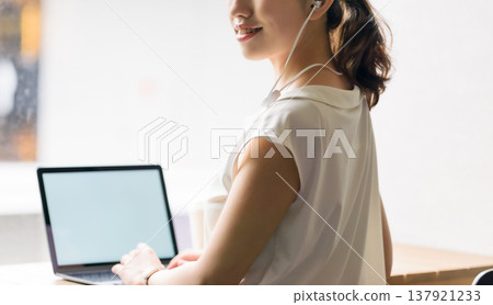A woman smiling while working on her computer. A woman smiling while working on her computer. 137921233