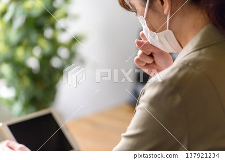 一名戴著口罩的女子正在看平板電腦。 137921234