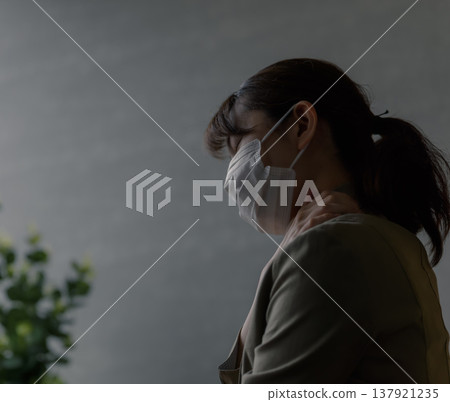 A woman endures shoulder pain at her desk. 137921235