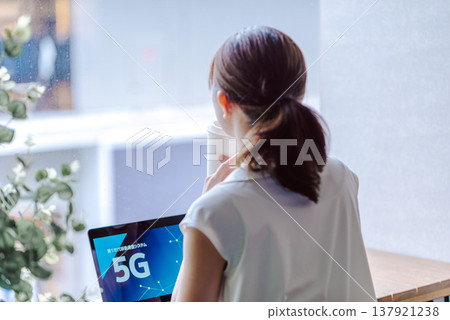 A woman is taking a break by the window, watching 5G. A woman is taking a break by the window, watching 5G. 137921238