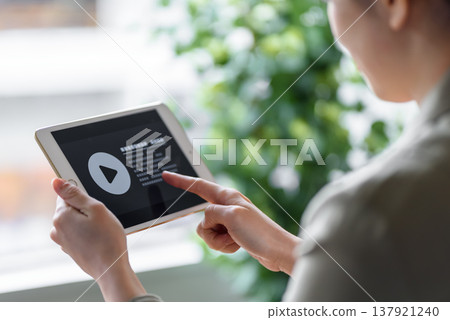 A woman watching video content on a tablet. 137921240
