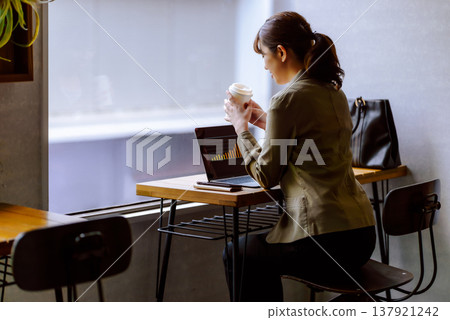 A woman checking data while drinking coffee at a cafe. 137921242