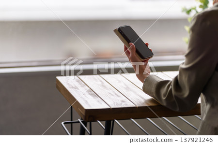 Hands holding a smartphone on a wooden table 137921246