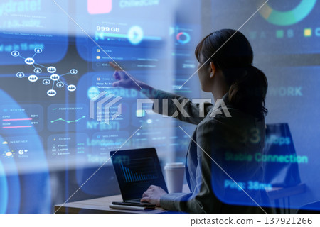 A businesswoman working on her laptop in a dimly lit cafe. 137921266