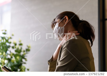 A woman suffering from stiff shoulders due to wearing a mask. 137921282