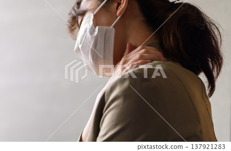 A woman wearing a mask complains of shoulder pain. 137921283