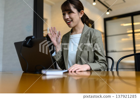 一位女士在網路會議中面帶微笑並揮手致意。 一位女士在網路會議中面帶微笑並揮手致意。 137921285
