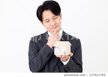 一位中年商人正在仔細端詳一棟獨立式住宅的模型。 一位中年商人正在仔細端詳一棟獨立式住宅的模型。 137921769