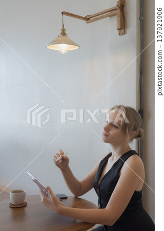 Casual young business woman using digital tablet while sitting at table in cafe Casual young business woman using digital tablet while sitting at table in cafe 137921906